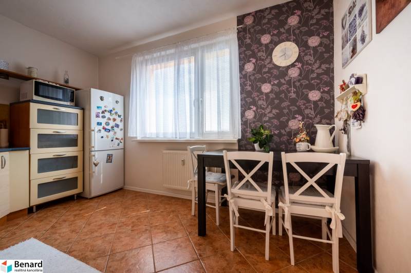 A kitchen in a 3-room apartment with a dining table, a plant, a refrigerator, and a microwave.