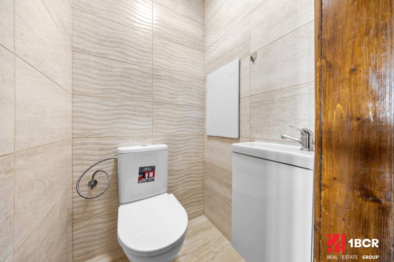 A toilet with ceramic tiles and a sink in a 3-room apartment.
