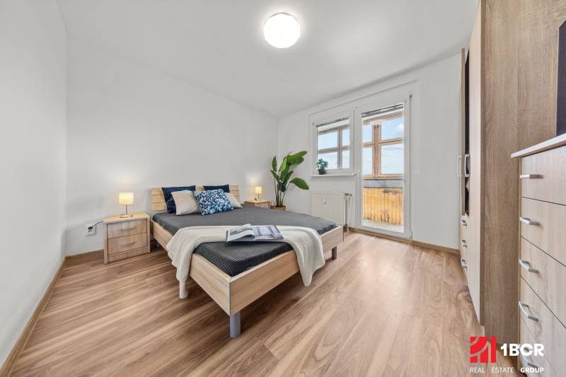 Bedroom in a 3-room apartment with a wooden bed and a balcony.