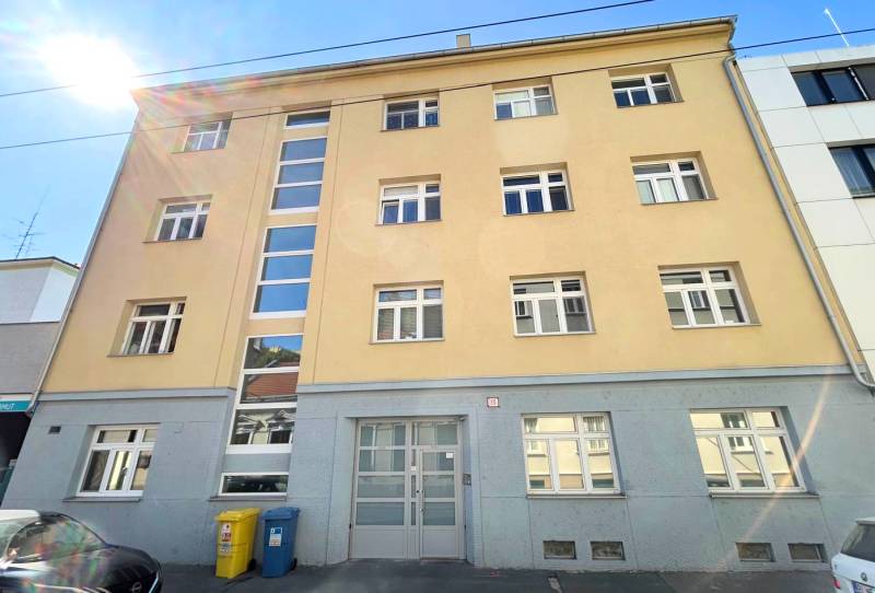 Building on Cintorínska Street in Bratislava – Old Town with parking and waste containers.
