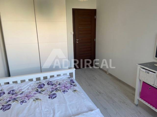 A bedroom in a 3-room apartment with a bed, a built-in wardrobe, and wooden doors.