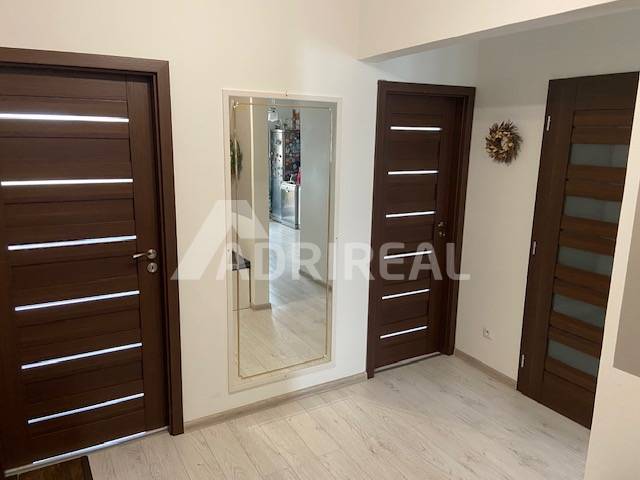 A hallway in a 3-room apartment with wooden doors and a mirror on the wall.