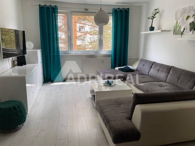 Living room with a sofa and television in a 3-room apartment, decorated with greenery and curtains.