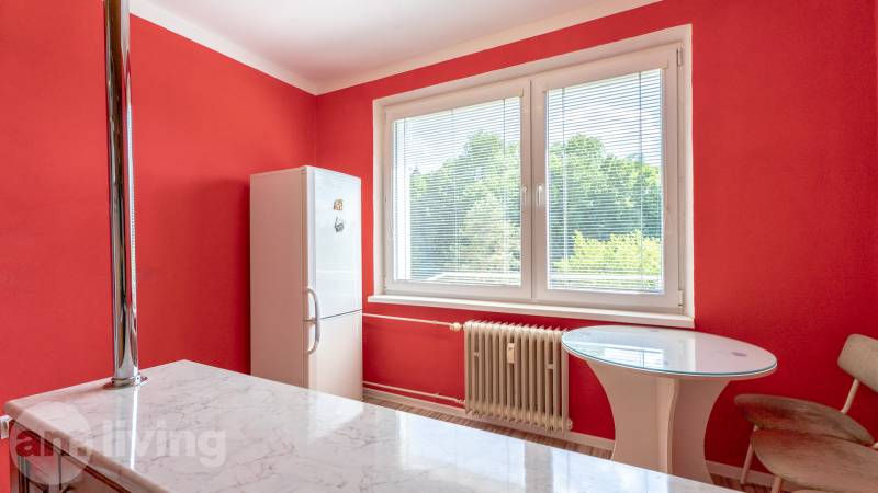 Red kitchen in a studio apartment with a window and seating at the table.