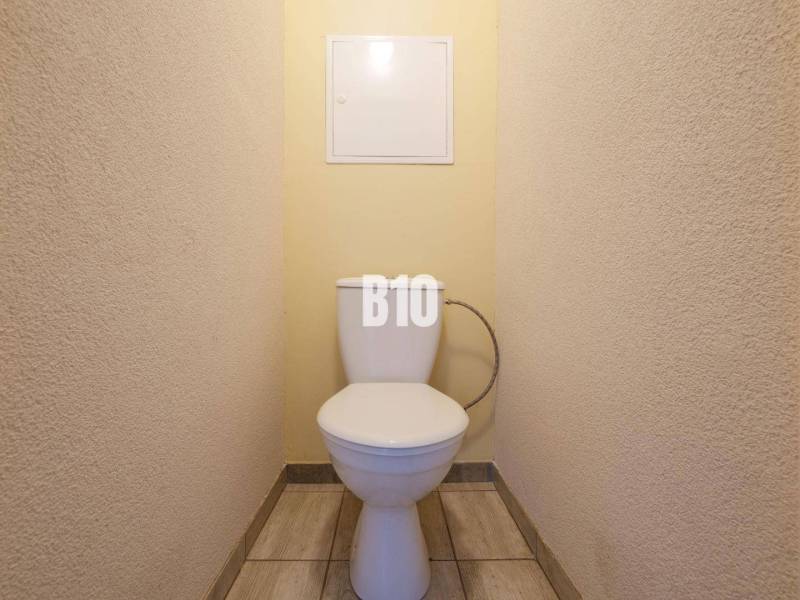 A bathroom in a one-room apartment with tiled flooring and light-colored walls.