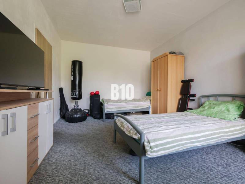 Two beds, a cabinet, a television, and a punching bag in a studio apartment.