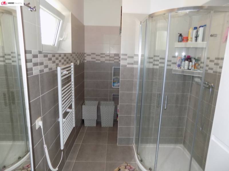 Shower enclosure and radiator in the bathroom of a family house with gray tiles.