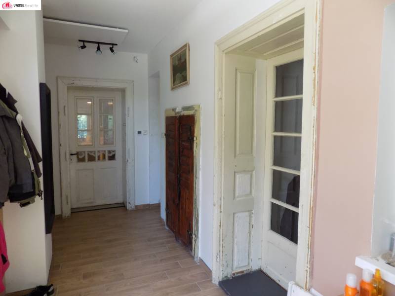 A hallway in a family house with a wooden floor and old doors.