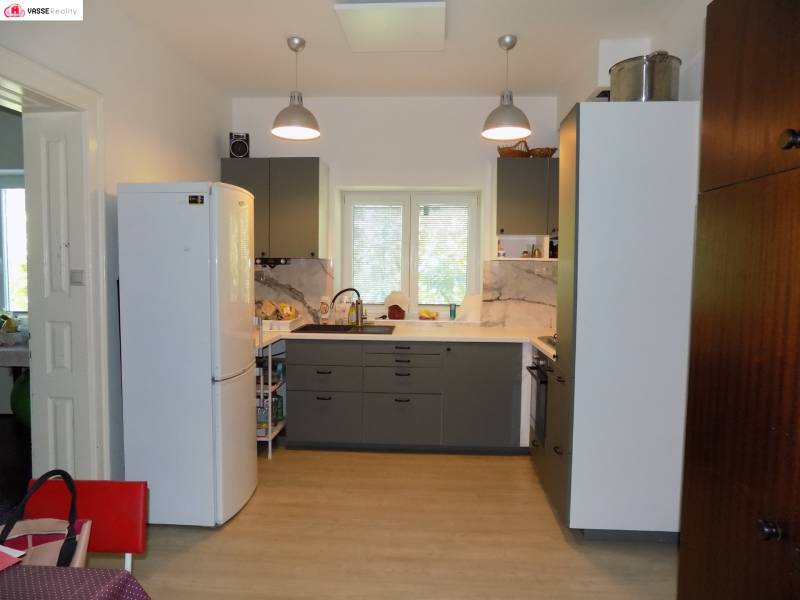 A kitchen in a family house with a white refrigerator, gray cabinets, and a window above the sink.