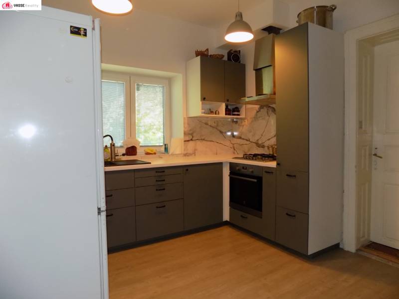 A kitchen in a family house with a gas stove, a white refrigerator, and a window with a view.