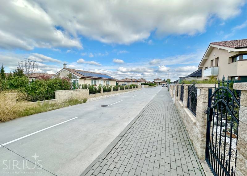 Južná Brána Street in Senec with family houses and a paved sidewalk. Plots - residential.