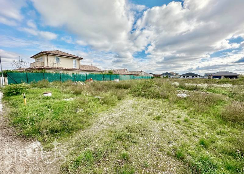 A residential plot in Senec at Južná Brána with a grassy area and fencing.