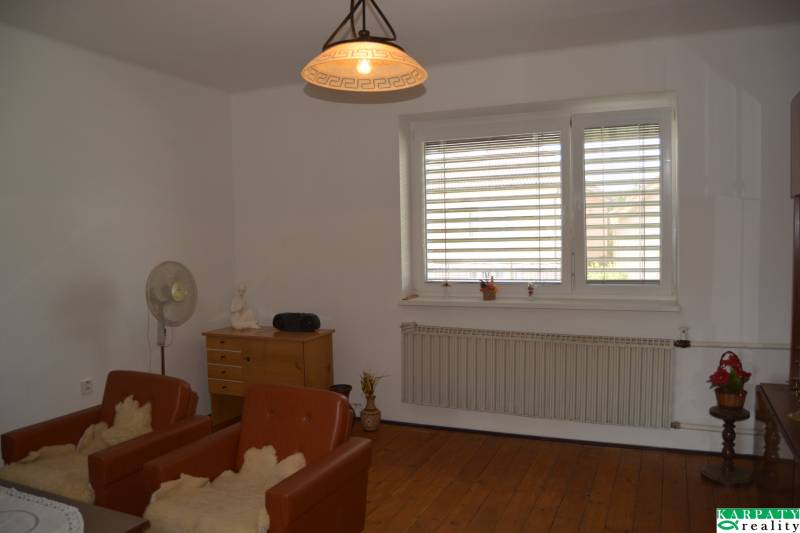 A room in a family house with a wooden floor, armchairs, and a large window.