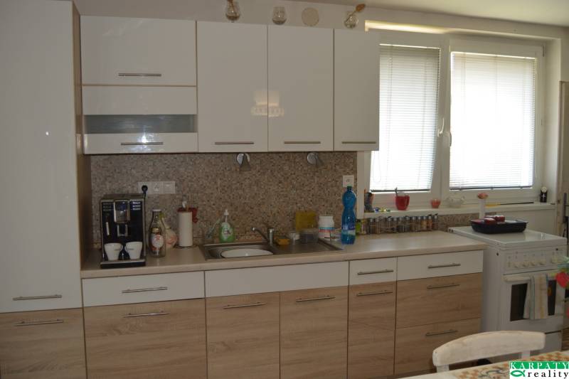 A kitchen in a family house with white and wooden cabinets and kitchen appliances.