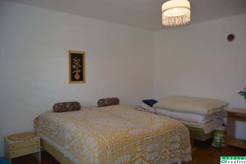 A bedroom in a family house with an ornate yellow bedspread and a ceiling light.