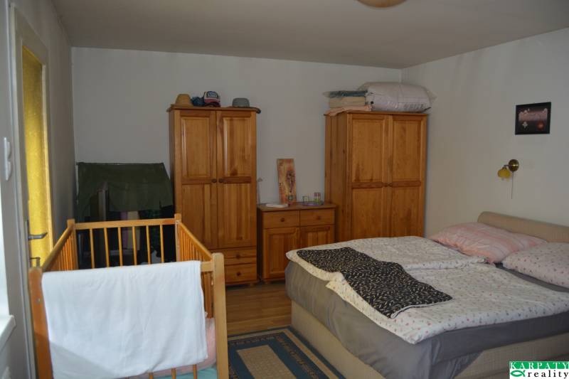 A bedroom in a family house with a wooden bed, cabinets, and a baby crib.