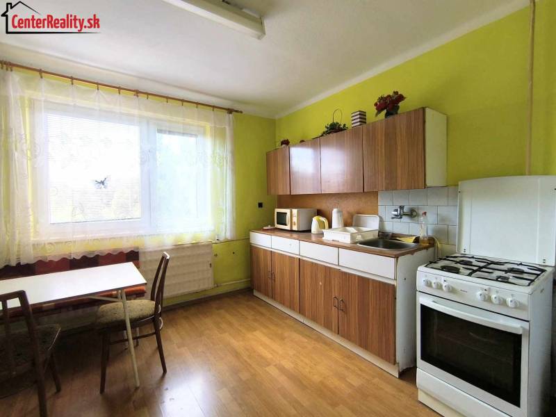 A kitchen in a family house with a window, a counter, and a stove, green walls.