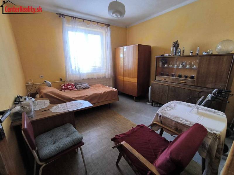 A room in a family house with a bed, antique furniture, and a table with a chair.