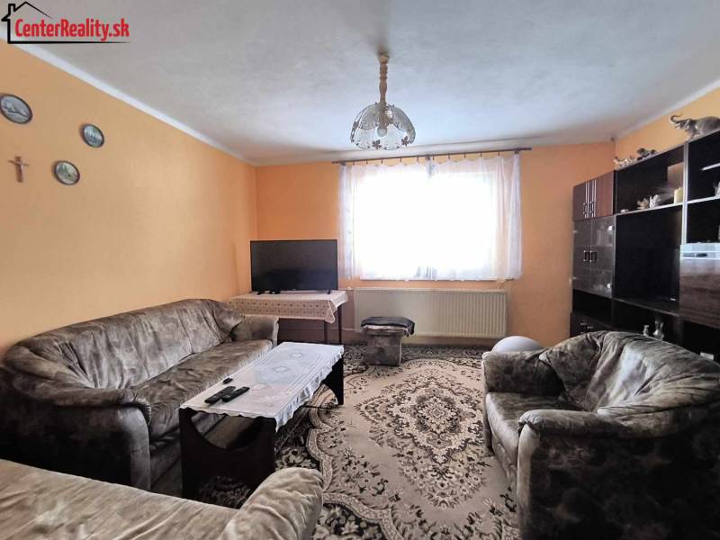 Living room in a family house with orange walls, sofas, and a carpet.