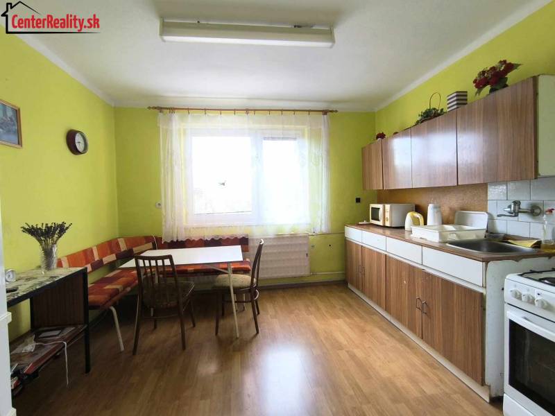 A kitchen in a family house with a table, chairs, kitchen unit, and a window.
