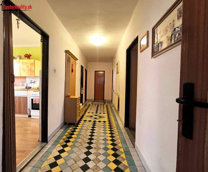 A hallway with colorful tiles, surrounded by rooms in a family house.