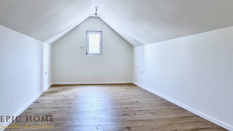 Attic room in a cottage with wooden floor and white walls.