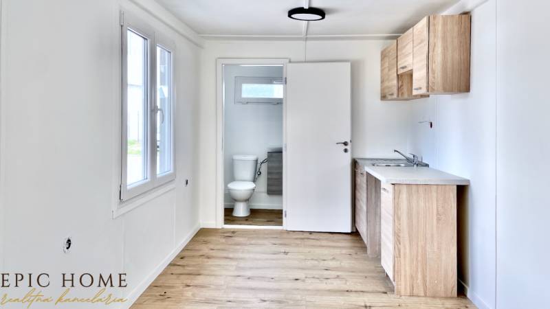 Interior of a cabin with wooden flooring, a kitchen counter, and an entrance to the bathroom.