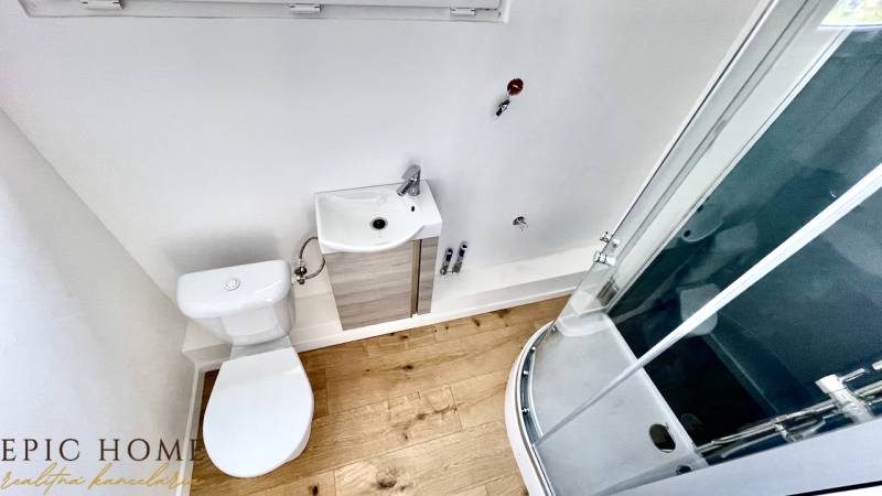 Bathroom in a cabin with a toilet, sink, and shower on a wooden floor.