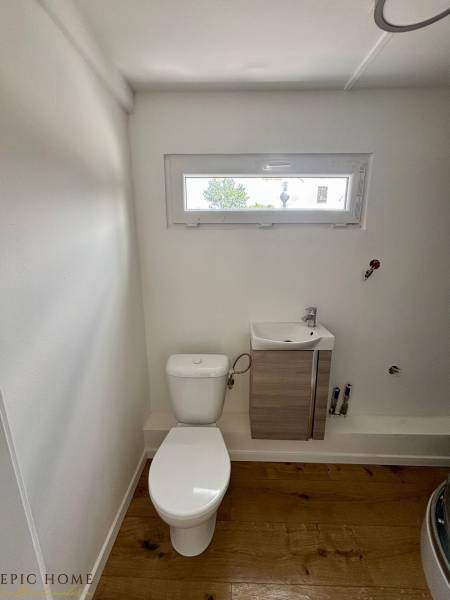 A toilet with a sink in the interior of a cabin and a wooden floor.