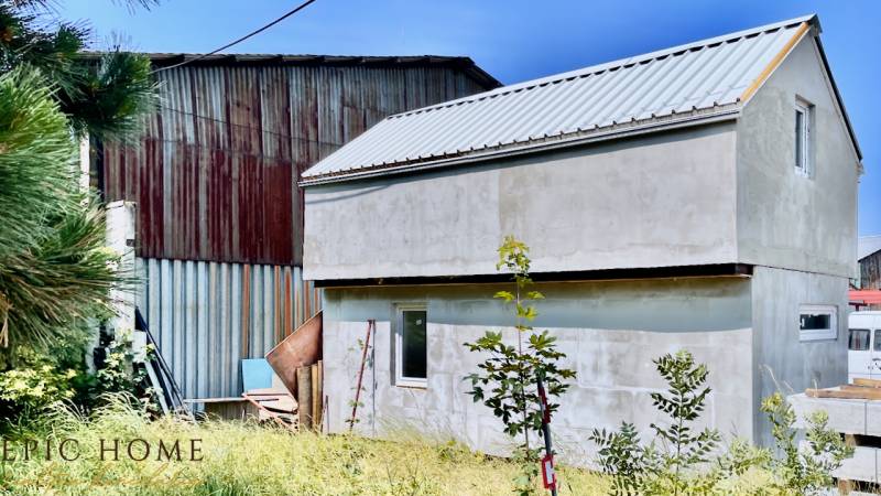 A cottage in Cífer surrounded by greenery, next to a metal structure, with a lawn in the foreground.