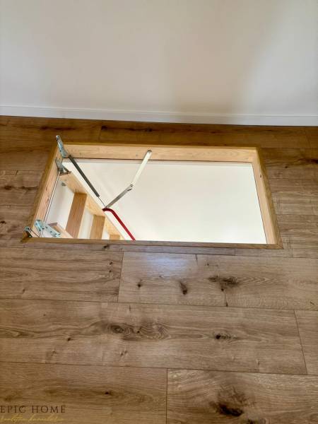 A ladder leading under the wooden floor in a cabin, with modern wooden paneling.