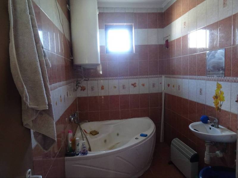A bathroom in a family house with a bathtub, a sink, and tiling.