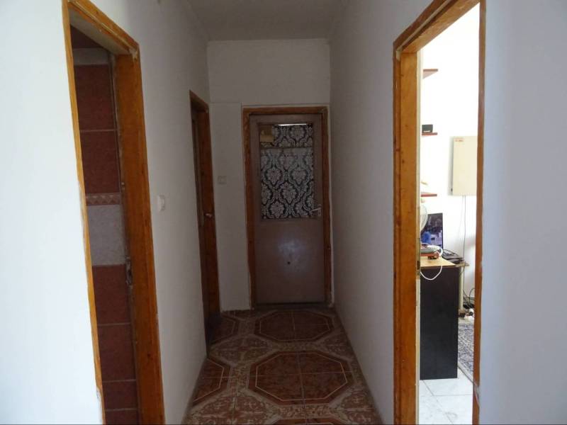 A hallway in a family house with wooden door frames and tiles.