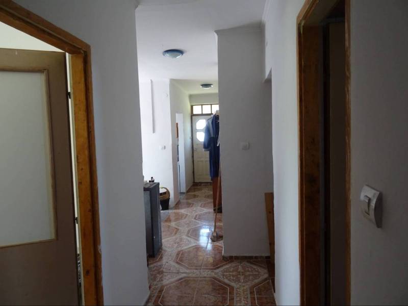 A corridor with tiles and white walls in a family house.