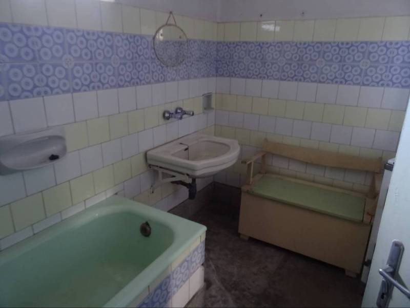 A bathroom in a family house with a bathtub, a sink, and a bench.