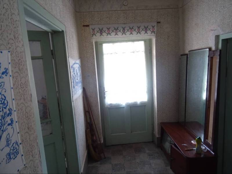 A hallway in a family house with wooden doors, a mirror, and decorative embroideries.