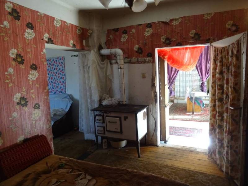 The interior of a family house with floral wallpaper and a traditional stove.