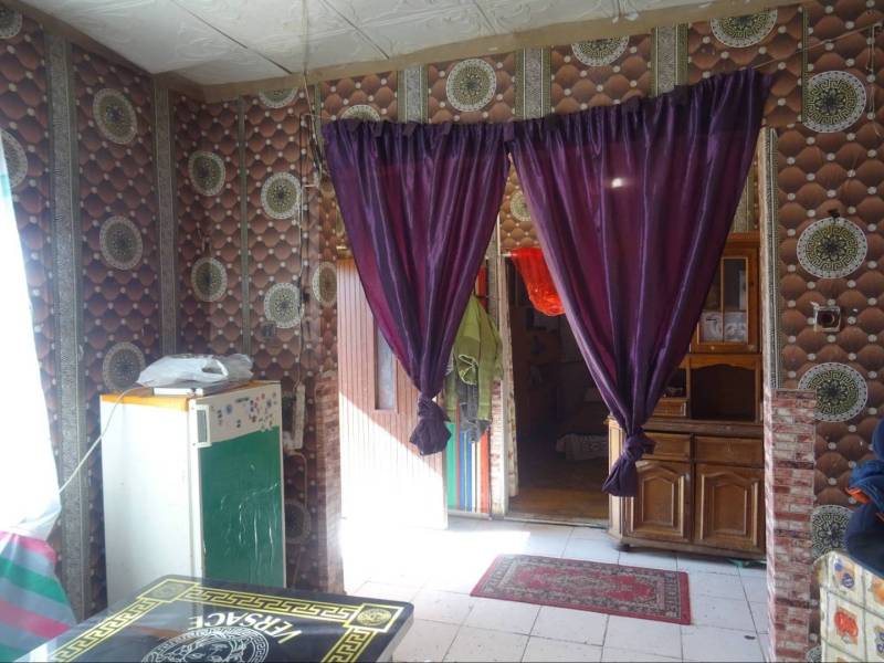 The interior of a family house with striking wallpaper, curtains, and wooden furniture.