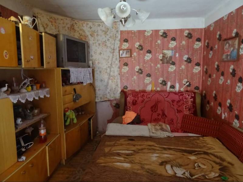 A room in a family house with floral wallpaper, a bed, and an old television.