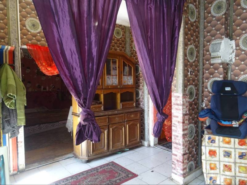A family house with purple curtains, a wooden dresser, and patterned walls.