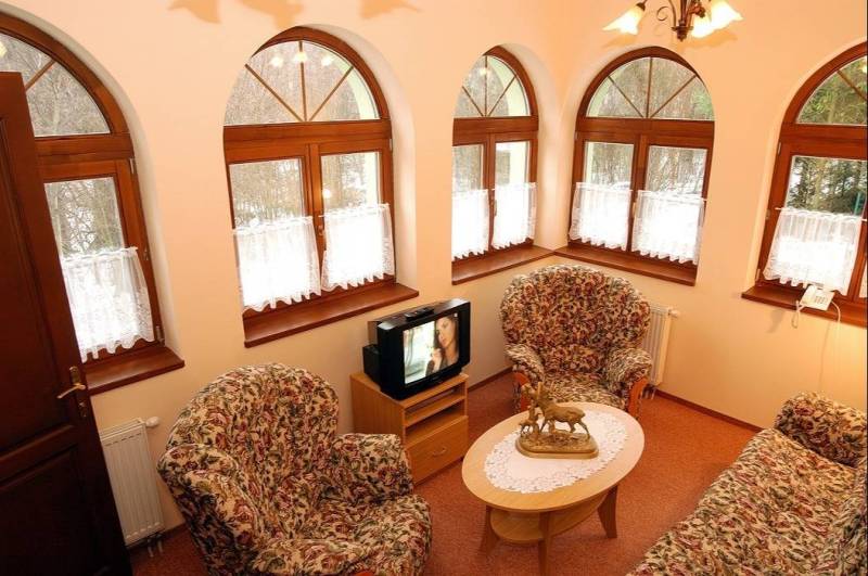 Interiors of hotels and guesthouses with armchairs, a table, and a television.
