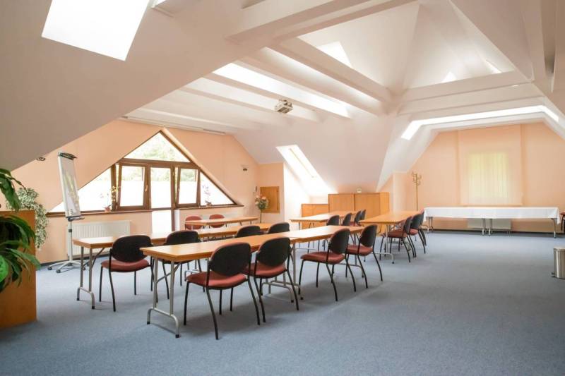 The interior of a conference room with windows, tables, and chairs in a hotel and guesthouse.