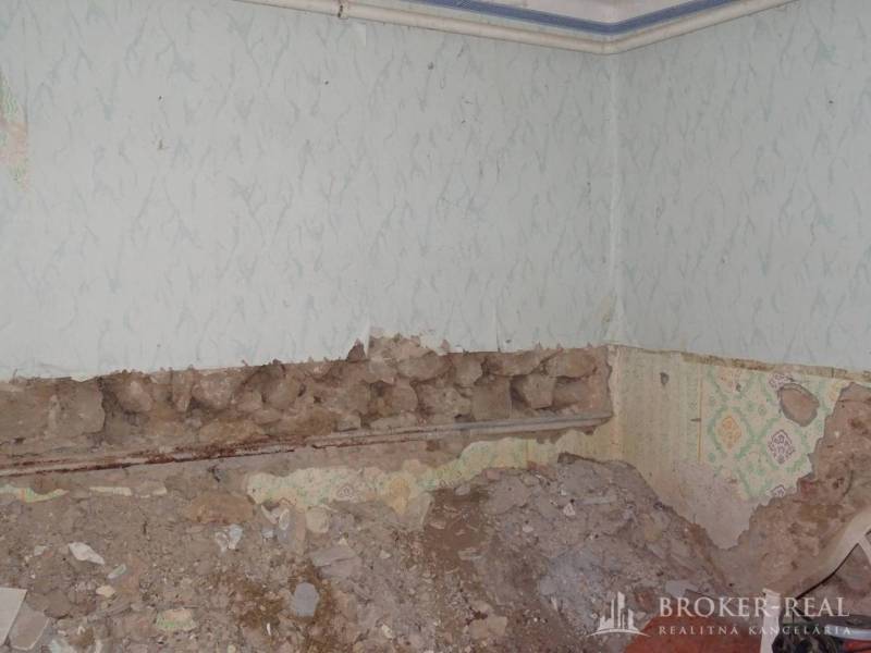 The interior of a family house with a wall in poor condition and damaged plaster cladding.