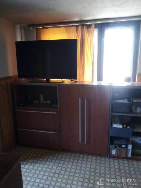 Living room in a family house with a cabinet, television, and curtains over the window.