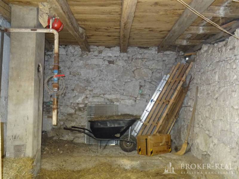 A tool shed in a family house with stone walls and a wooden ceiling.