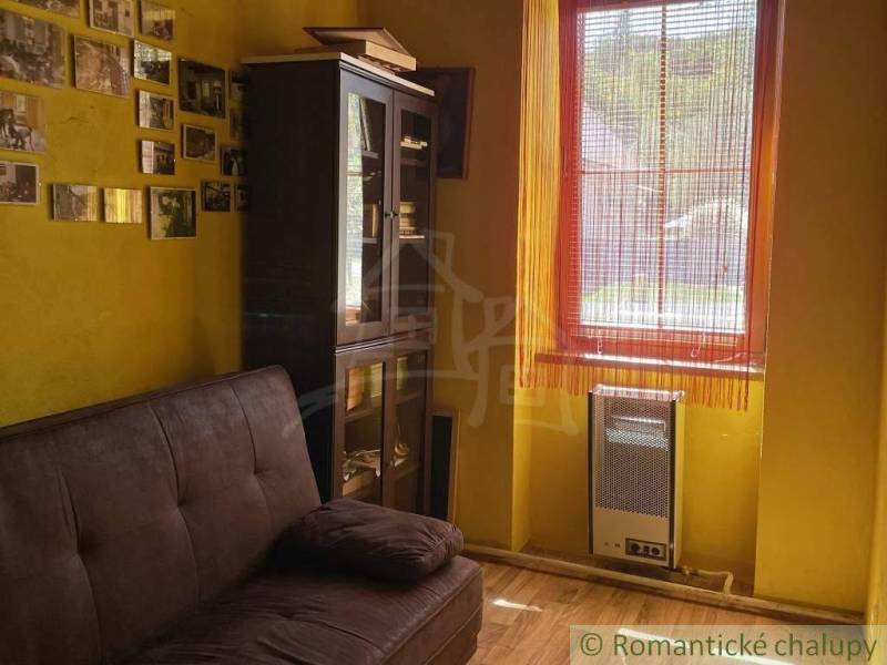 Yellow room in a family house with a sofa, display cabinet, and photos on the wall.