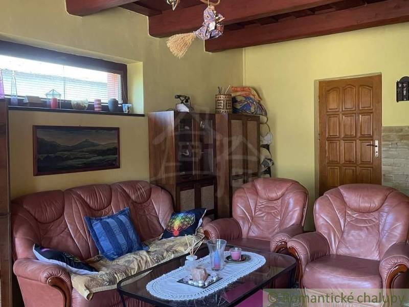 Living room in a family house with brown leather furniture and wooden beams.