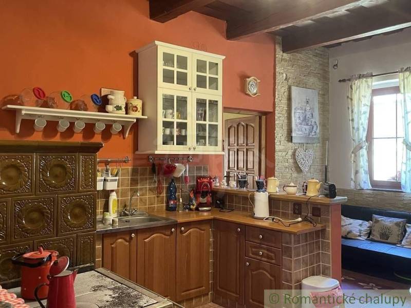 A kitchen in a family house with a wooden cabinet, a ceramic stove, and hanging shelves.