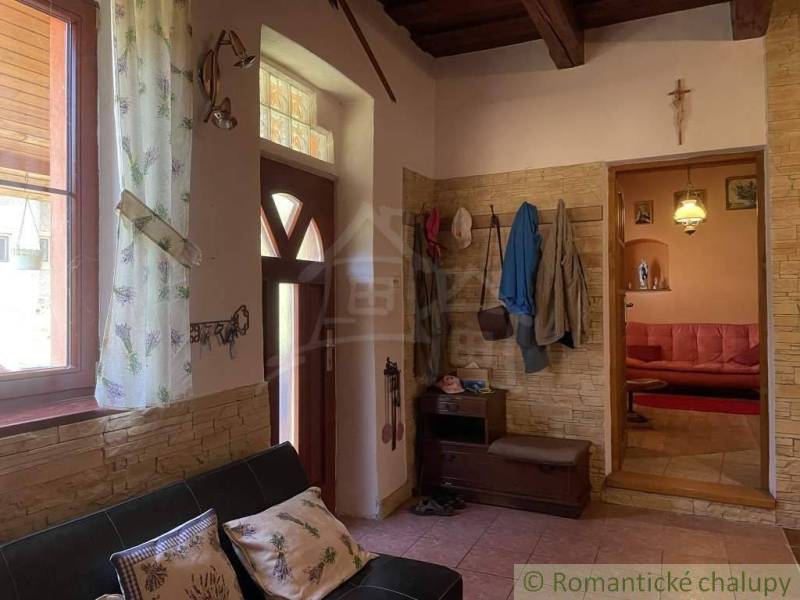 Interior of a family house with a wooden ceiling, coat rack, sofa, and decorations.