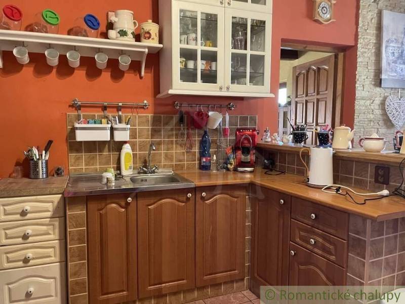 A kitchen in a family house with wooden furniture and an orange wall.
